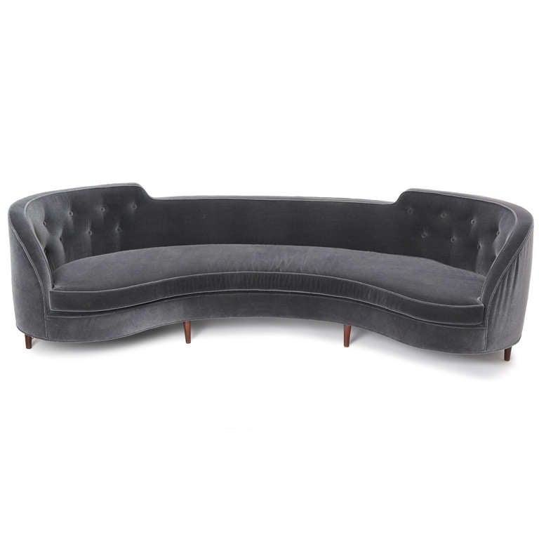 A generously proportioned Oasis sofa that features a distinctive crescent shape accented by raised ends, the entire form floating atop seven turned dowel legs. 

Upholstered in a rich blue - grey mohair.